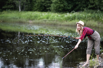 Girl by the river with a fishing rod