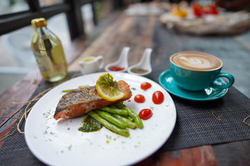 A coffee cups with a coffee latte and delicious salmon for breakfast at the café