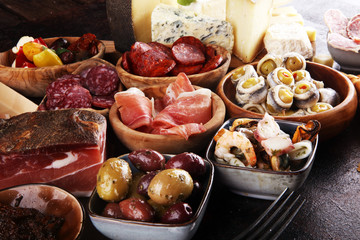 Italian antipasti wine snacks set. Cheese variety, Mediterranean olives, seafood salad, Prosciutto di Parma, tomatoes, anchovy and wine in glasses