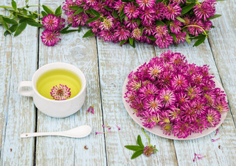 Traditional Herbal Tea of Red Clover Flowers (Trifolium pratense). Fresh Clover Flower Tea in a white cup. Purple Wildflowers bouquet on a wooden rustic table. Phytotherapy Medicinal Herbs 