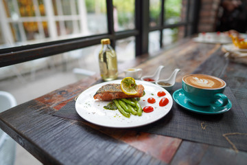 A coffee cups with a coffee latte and delicious salmon for breakfast at the café