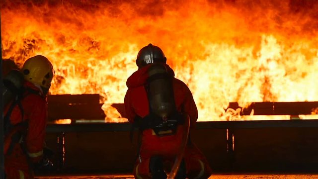 Firefighter on duty in Burning Building. Two firefighters fighting a fire with a hose and water during firefighting. Firefighters during battle and explosion of fire emergency case for danger mission.