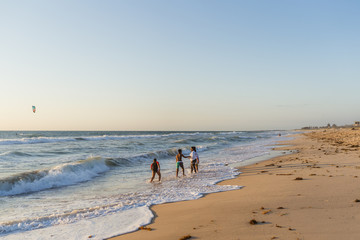 Young children having an adventure and playing in the shallow waves on the beach in the evening sunset at Scarborough beach, Perth, Western Australia. 