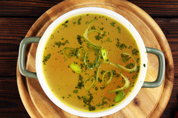 Broth with carrots, onions various fresh vegetables in a pot - colorful fresh clear spring soup. Rural kitchen scenery vegetarian bouillon stock