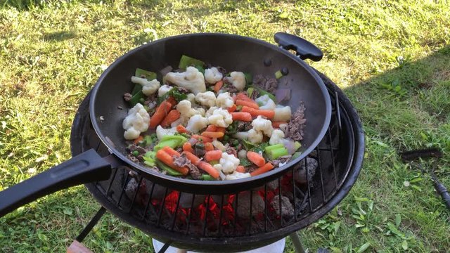 Cooking outdoors in a wok on a coal grill