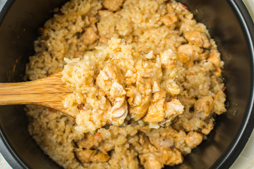 Ready pilaf with crumbly rice and wooden spoon after cooking in slow cooker.