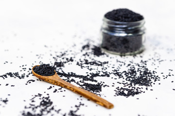 Black sesame seeds in a wood spoon with white background