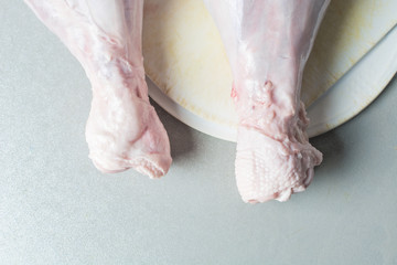 Thawed raw turkey legs on white cutting board for cooking.