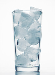 one glass of water full of ice cubes, white background, blue toned object