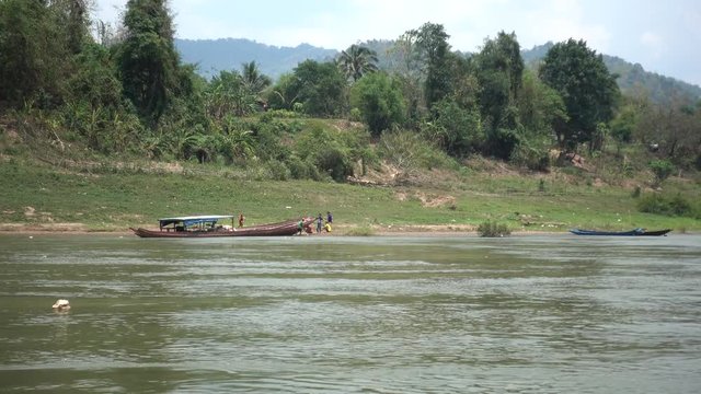 Laos Local People Working on a Boat on Mekong River, with a Hat Floating by in the Water