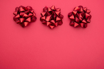 Red ribbons bows over red background, flat lay. Party, birthday, Christmas or Valentine's Day pattern. Flat lay.