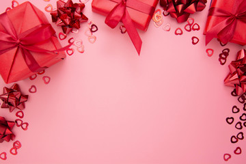 Red gift boxes with ribbon on pink background, flat lay, Valentine's Day, copy space. Frame, border, mock up.