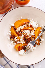 Winter dessert. caramelized persimmon with walnuts and cottage cheese