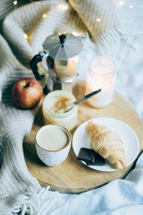 Cozy winter weekend breakfast, coffee and croissant on wooden tray