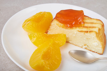 A portion of cottage cheese casserole with strawberry jam and peaches
