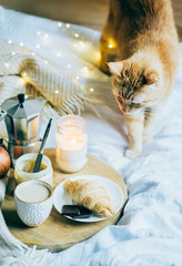 Cozy winter weekend breakfast, coffee and croissant on wooden tray