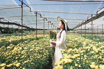 Portrait young beautiful asian woman in white dress relaxing at chrysanthemum flower garden