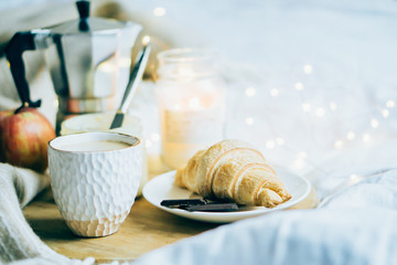 Cozy winter weekend breakfast, coffee and croissant on wooden tray