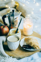 Cozy winter weekend breakfast, coffee and croissant on wooden tray