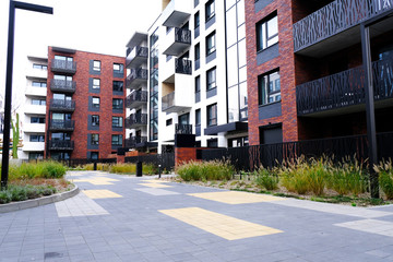 Courtyard of modern apartment buildings district with sidewalk and green grass.