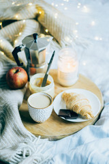Cozy winter weekend breakfast, coffee and croissant on wooden tray