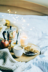 Cozy winter weekend breakfast, coffee and croissant on wooden tray