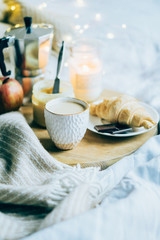 Cozy winter weekend breakfast, coffee and croissant on wooden tray