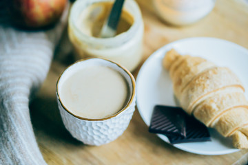 Cozy winter weekend breakfast, coffee and croissant on wooden tray