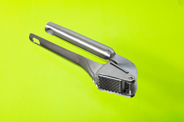 Metal press for garlic isolated on green background