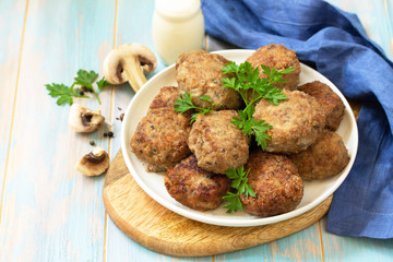 Homemade meatballs with mushrooms on the kitchen wooden table. Copy space.
