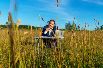 White caucasian man with a beard works at table on a laptop outdoors. Concept businessman outdoors.