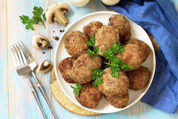 Homemade meatballs with mushrooms on the kitchen wooden table. Top view of a flat lay.