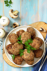 Homemade meatballs with mushrooms on the kitchen wooden table. Top view of a flat lay. Copy space.