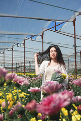 Portrait young beautiful asian woman in white dress relaxing at chrysanthemum flower garden