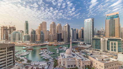 Naklejka na ściany i meble Yachts in Dubai Marina flanked by the Al Rahim Mosque and residential towers and skyscrapers aerial timelapse.