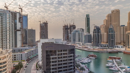 Yachts in Dubai Marina flanked by the Al Rahim Mosque and residential towers and skyscrapers aerial timelapse.