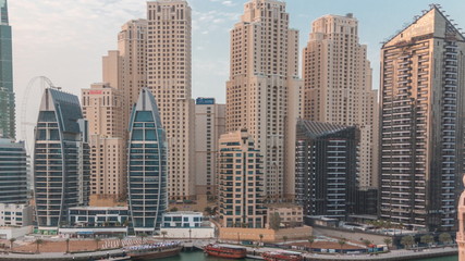 Fototapeta premium Yachts in Dubai Marina flanked by the Al Rahim Mosque and residential towers and skyscrapers aerial timelapse.