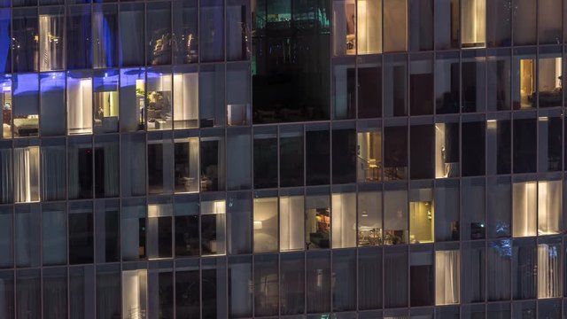 Night view of office and apartment building timelapse. High rise skyscraper with blinking windows with people moving inside. Aerial view from above. Zoom in