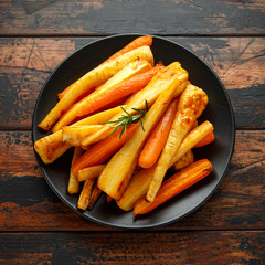 Roasted Parsnips and Carrots with herbs on rustic wooden table