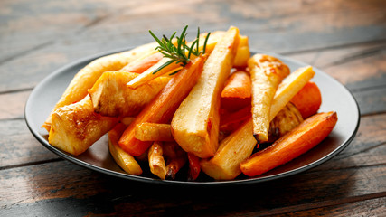 Roasted Parsnips and Carrots with herbs on rustic wooden table