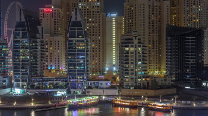 Luxury yachts parked on the pier in Dubai Marina bay with city aerial view night timelapse