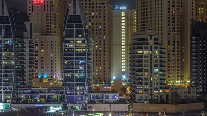 Fototapeta na wymiar Luxury yachts parked on the pier in Dubai Marina bay with city aerial view night timelapse