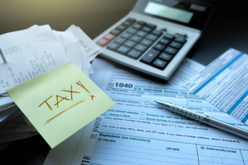 ellow note has the text of tax written with red pen put on the receive bill and blank form for tax filing, calculator and pen. This annual job very important for accounting and financial department