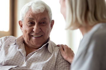 Smiling elder male patient communicating with nurse.
