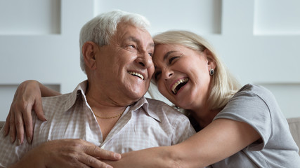 Overjoyed middle aged woman cuddling happy older 80s father.