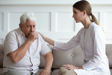 Medical worker visiting older unhealthy male patient at home.