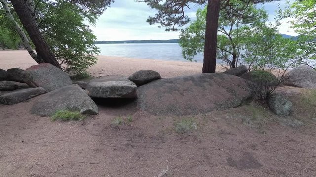 The beach of the lake near the mountains, rocks and trees in Borovoe, Kazakhstan