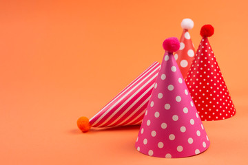 Colorful birthday caps on orange background.