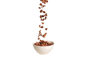 Chocolate corn flakes falling to the white bowl isolated on white. Motion.