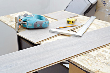 DIY, repair, building and home concept - close up of male hands lying parquet floor board/laminate flooring